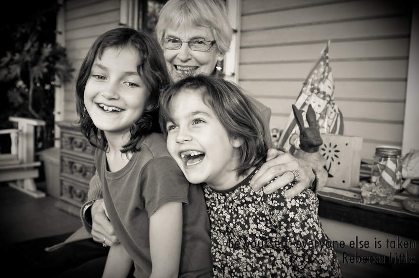 Black and white photograph of girls laughing with grandmother