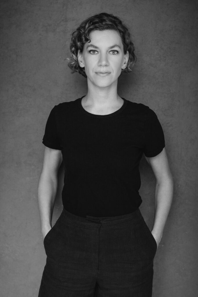 This strong black and white branding image is striking. L is wearing a simple black t-shirt and cropped dark jeans. She's standing and looking directly at the camera, unsmiling. her hand on her in her pockets. I've heard photographers recommend against wearing black for headshots, but it works perfectly for the right person. This images illustrates that clothes for headshots determine the mood of the photo along with lighting and background. This editorial portrait was created by Rebecca Little Photography in Pasadena, CA.