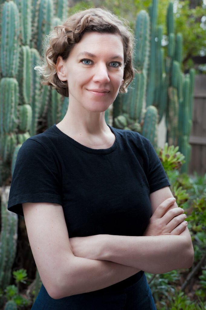 This outdoor headshot was created by Rebecca Little Photography Pasadena, CA for a children's book author. She's standing in fron of cactus and wearing a black t-shirt and blue jeans.