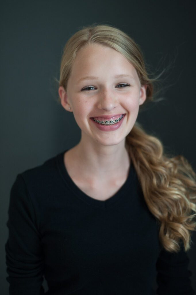 This is a middle school teen photo of a young girl. She has long blond hair pulled back in a pony tail and she's laughing. She has braces. Image created by Rebecca Little Photography Pasadena, CA.
